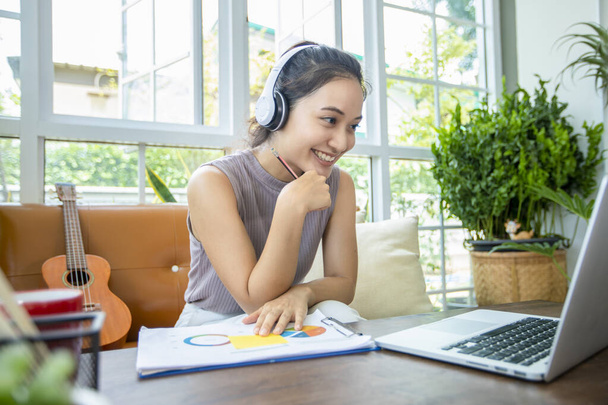 Azjatyckie biznesmenki używają notebooków i noszą słuchawki do spotkań online i pracy w domu. - Zdjęcie, obraz