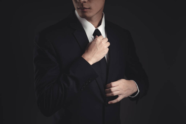 Nahaufnahme eines Geschäftsmannes im schwarzen Anzug. Elegant hübsch auf schwarzem Hintergrund. - Foto, Bild