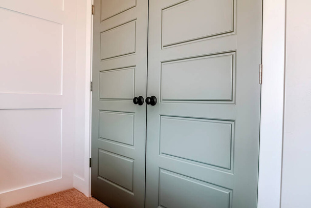 Двойные двери с наконечниками и черной круглой дверной ручкой у входа в спальню - Фото, изображение