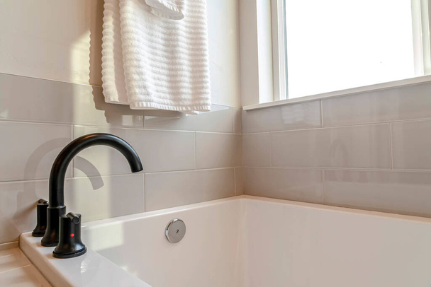 Robinet incurvé noir et baignoire intégrée dans la salle de bain intérieure avec mur de tuiles blanches - Photo, image