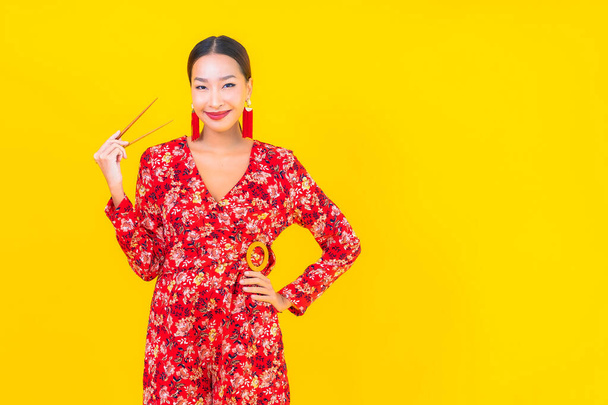 Portret mooie jonge aziatische vrouw met eetstokjes op kleur geïsoleerde achtergrond - Foto, afbeelding