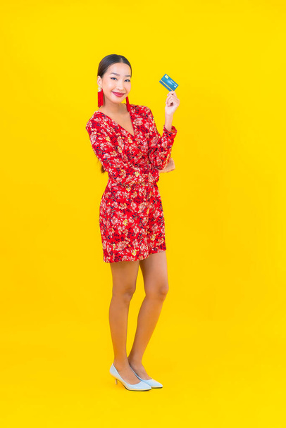 Muotokuva kaunis nuori aasialainen nainen luottokortti ostoksia keltainen eristetty tausta - Valokuva, kuva