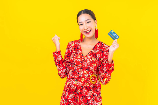 Ritratto bella giovane donna asiatica carta di credito per lo shopping su sfondo giallo isolato - Foto, immagini