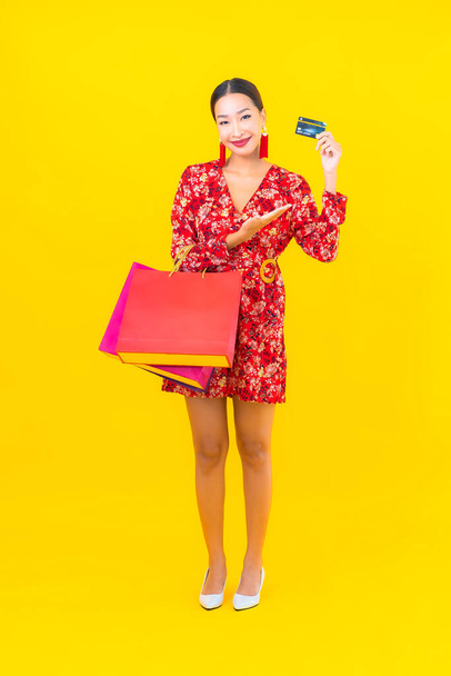 Retrato hermosa joven mujer asiática con colorido bolso de compras sobre fondo amarillo - Foto, imagen