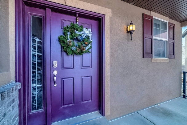 Vivida porta d'ingresso viola con ghirlanda e luce laterale alla facciata di ingresso della casa - Foto, immagini