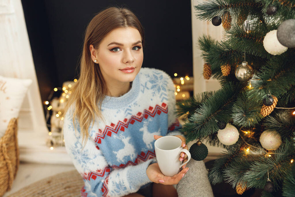 Close up of girl wears festive clothes take cup of coffee at home near Christmas Tree - Fotoğraf, Görsel