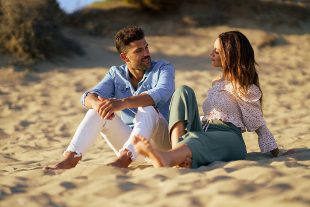 Atractiva pareja sentada en la arena de la playa - Foto, Imagen