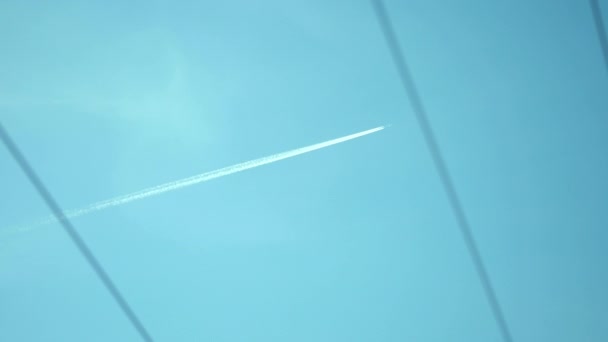 Dreaming of freedom and far destinations and lands. Low angle pov handheld of airplane contrails against blue sky between city electric wires. Pickup shot depicting journey, travel, and high altitude. - Footage, Video
