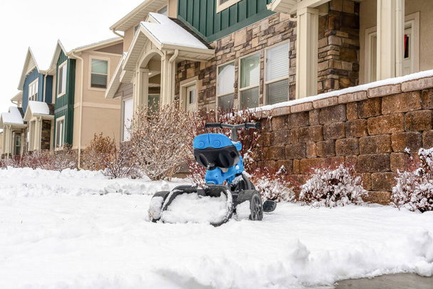 Drie wiel speelgoed fiets voor kinderen op de binnenplaats van het appartement op een besneeuwde winterdag - Foto, afbeelding