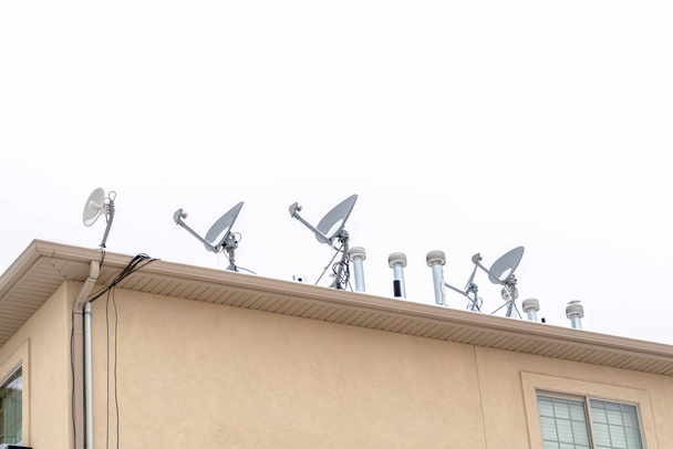 Platos satélite en la azotea del edificio residencial contra el cielo nublado - Foto, imagen