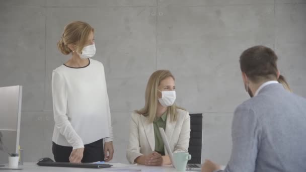 Skupina podnikatelů má schůzku a pracuje v kanceláři a nosí masky jako ochranu před koronavirem - Záběry, video