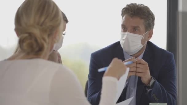Gruppo di uomini d'affari hanno un incontro e di lavoro in ufficio e indossare maschere come protezione dal coronavirus - Filmati, video