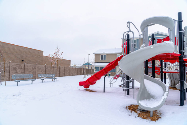 Scivoli su un parco giochi per bambini con panchine contro il paesaggio innevato in inverno - Foto, immagini
