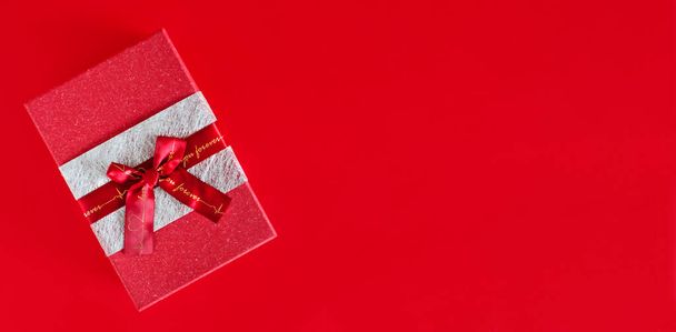 czerwone pudełko z kokardą na czerwonym tle. przestrzeń kopiowania - Zdjęcie, obraz