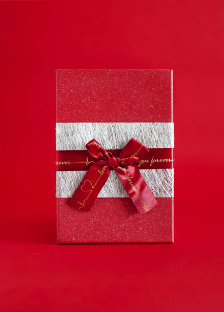red gift box with a bow on a red background. centered - Foto, imagen