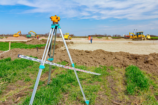 Surveyor instrument and leveling lath are used for measuring level on construction site. Surveyors ensure precise measurements before undertaking large construction projects. - Photo, Image
