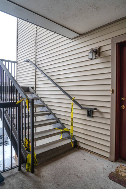 Konut binasının dış merdivenlerinde sarı uyarı inşaat bandı var. - Fotoğraf, Görsel