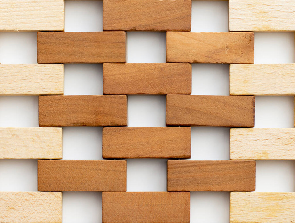 Ściana wykonana z małych drewnianych cegieł. Brązowe i naturalne drewniane klocki przypominające ścianę cegieł na białym tle. Teksturę. Kontekst. - Zdjęcie, obraz