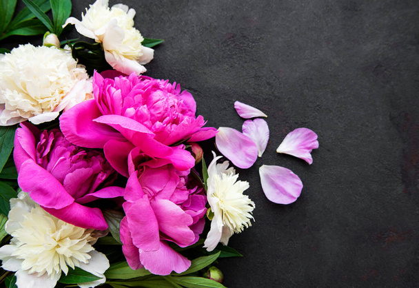 Fresh pink peony flowers border with copy space on black background, flat lay.  - Photo, Image