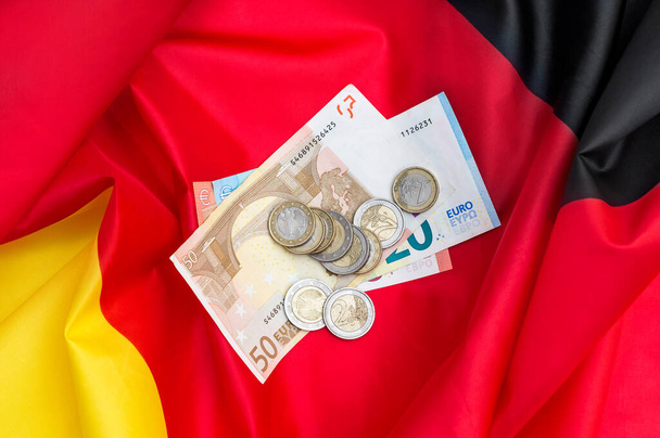 Des billets en euros avec des pièces sur le drapeau allemand. Vue du dessus. - Photo, image