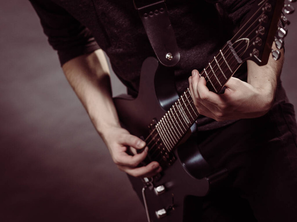 Male hands with electric guitar. Close up, part body adult person is holding instrument and playing. Hobby, music concept - Фото, зображення