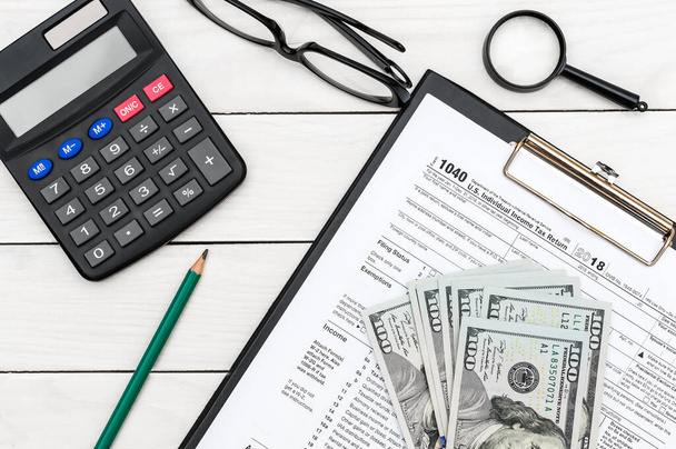 Кліпборд з податковою формою, калькулятор, гроші та окуляри на білому офісному столі. Вид зверху. Концепція бізнесу
. - Фото, зображення