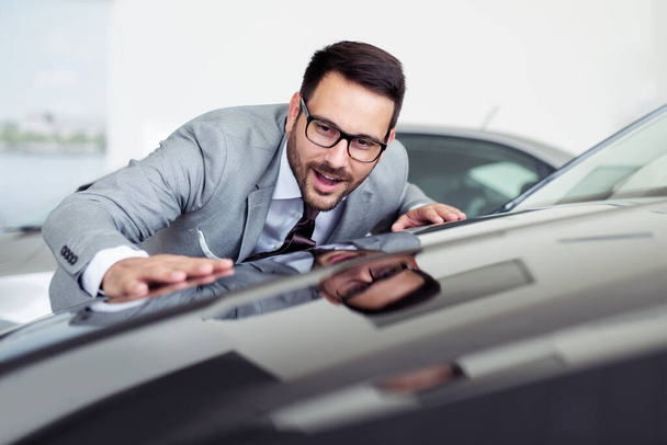 Young business man is choosing a new vehicle in car dealership. - Фото, изображение