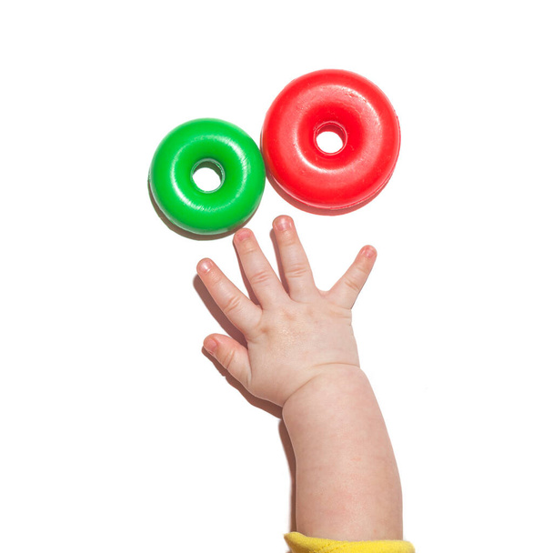 Рука ребенка тянется к игрушкам. Детская ладонь на белом фоне - Фото, изображение