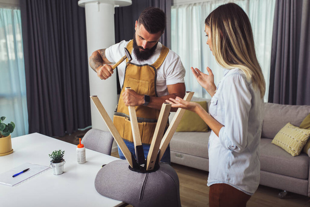 Vaimo auttaa aviomiestä korjaamaan rikki tuoli kotona - Valokuva, kuva