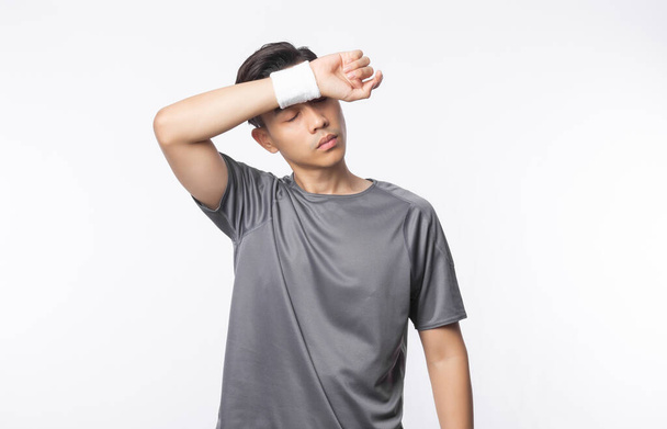 Jovem asiático homem em roupas esportivas cansado após o exercício isolado no fundo branco. - Foto, Imagem
