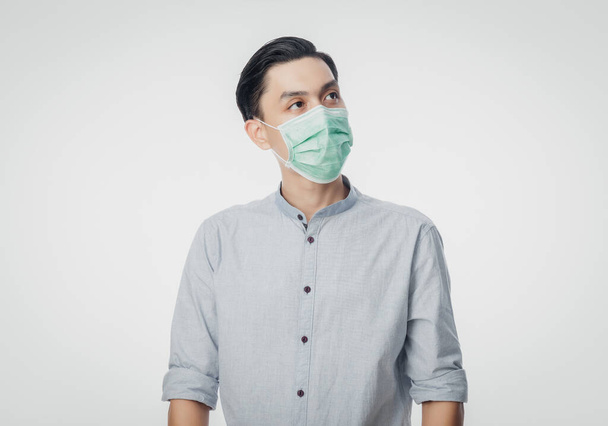 Young Asian Businessman wearing hygienic mask and looking up to prevent infection, 2019-nCoV or coronavirus. Airborne respiratory illness such as pm 2.5 fighting and flu isolated on white background. - Photo, image