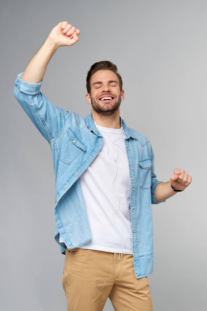 Close up portrait of cheerful young man enjoying listening to music wearing casual jeans outfit - Φωτογραφία, εικόνα