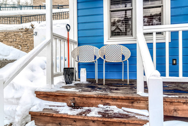 Židle proti modré stěně domu s vlhkou a zasněženou verandou a schody v zimě - Fotografie, Obrázek