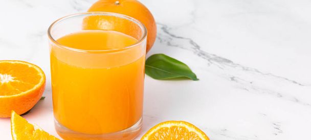 Jugo de naranja fresco en vidrio y naranjas fruta sobre fondo de banner de mesa de mármol blanco con espacio de copia. - Foto, Imagen