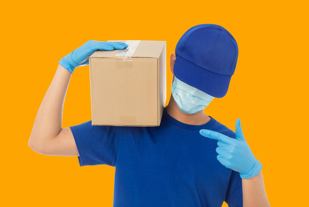 Delivery man hand in medical gloves and wearing mask holding cardboard box mockup template, Delivery service concept. - Photo, Image