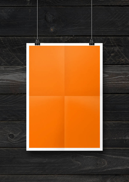 Orange folded poster hanging on a black wooden wall with clips. Blank mockup template - Fotó, kép