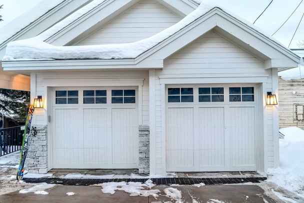 Inicio exterior con paredes blancas techos a dos aguas y dos puertas de garaje acristaladas - Foto, imagen