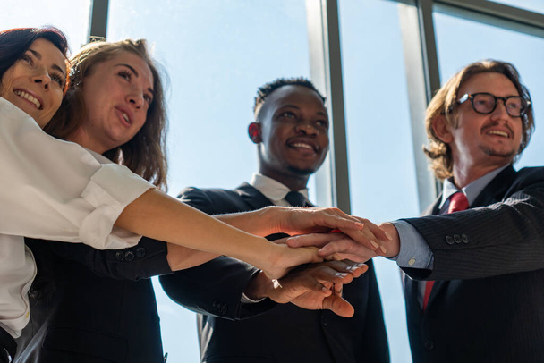 équipe d'affaires multiethnique, y compris les hommes, les femmes, les africains et les caucasiens toucher les mains comme un signe d'intégrité et d'unité de l'entreprise - Photo, image