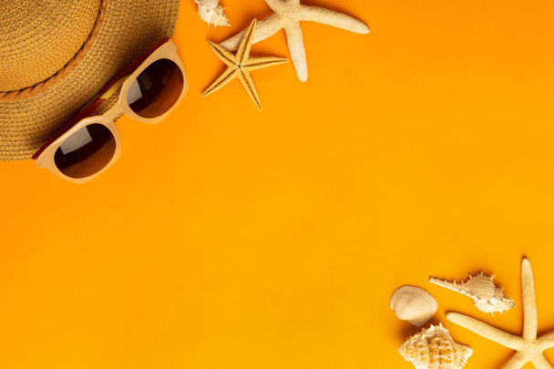 Fondo de verano con accesorios de playa sombrero de paja, gafas de sol sobre fondo naranja vibrante vista superior con espacio de copia. - Foto, Imagen