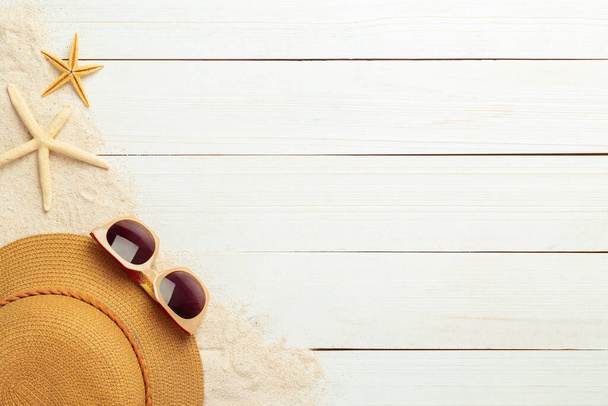 Καλοκαιρινό φόντο με αξεσουάρ παραλίας - ψάθινο καπέλο, γυαλιά ηλίου σε λευκό ξύλινο τραπέζι. - Φωτογραφία, εικόνα