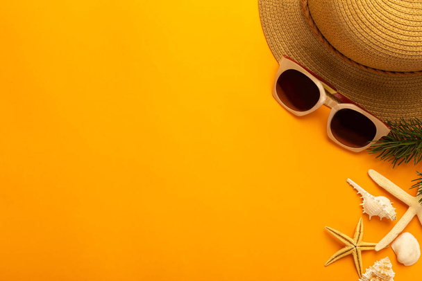 Fondo de verano con accesorios de playa sombrero de paja, gafas de sol sobre fondo naranja vibrante vista superior con espacio de copia. - Foto, Imagen