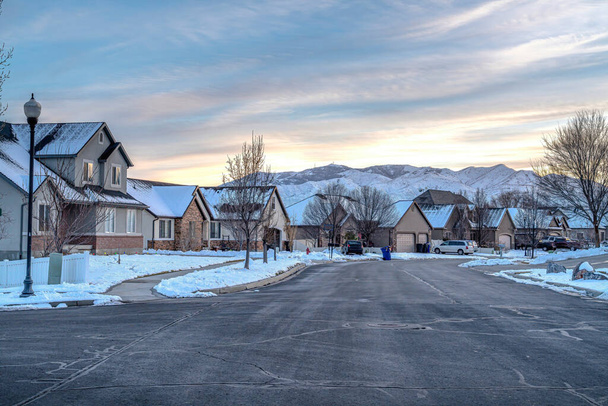 Улица с дорогой вдоль домов с видом на горы и облачное небо - Фото, изображение