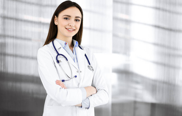 Smiling young woman-doctor is filling up medical recommendations using a clipboard. Therapist at work in a clinic office. Medicine concept - Photo, Image