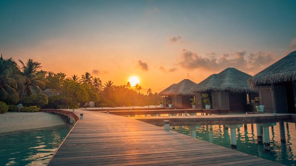 Pôr do sol na ilha das Maldivas, luxuoso resort de moradias aquáticas e cais de madeira. Céu bonito e nuvens e fundo de praia para férias de verão férias e conceito de viagem - Foto, Imagem