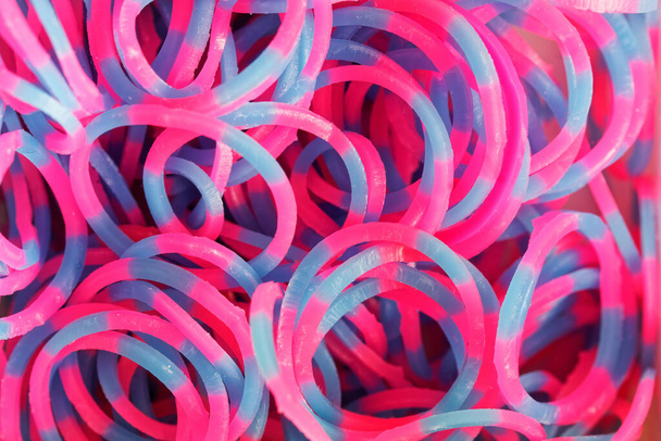 Lots of red and blue rubber bands for bracelets or charms. Children's hobby and handicraft. Subject for the development of fine motor skills of hands. Close-up. Macro. Background or backdrop. - Photo, Image