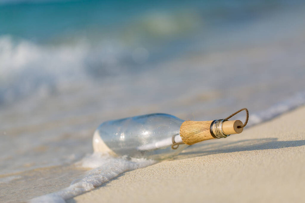 Butelka z wiadomością. Idylliczna koncepcja ucieczki, butelka unosi się w linii surfingowej. Zagubiony w przyrodzie, tropikalne wybrzeże z miękkim piaskiem i słonecznym szablonem - Zdjęcie, obraz