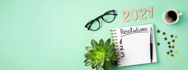 New year 2021 goals on desk. 2021 goals with open notebook, coffee cup, eyeglasses, plant succulent on green background. Goals, resolutions, plan, strategy, idea concept. New Year 2021 template - Photo, Image