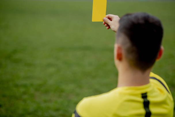 Referee showing a red card to a displeased football or soccer player while gaming. Concept of sport, rules violation, controversial issues, obstacles overcoming - Foto, Bild