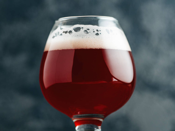 Cerveza cereza en un vaso pequeño sobre un fondo de hormigón oscuro - Foto, imagen