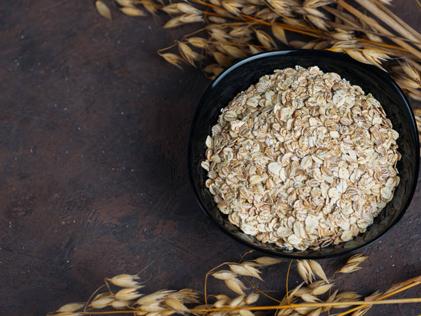 Oat flakes and ears of oats. Oatmeal in a plate on the table. Healthy breakfast - Photo, Image